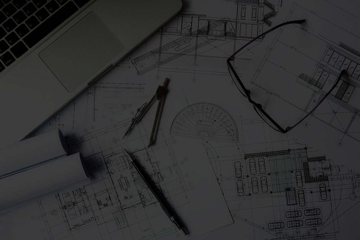 Architectural floor plans and elevations spread across a desk with a drawing compass, protractor and reading glasses.